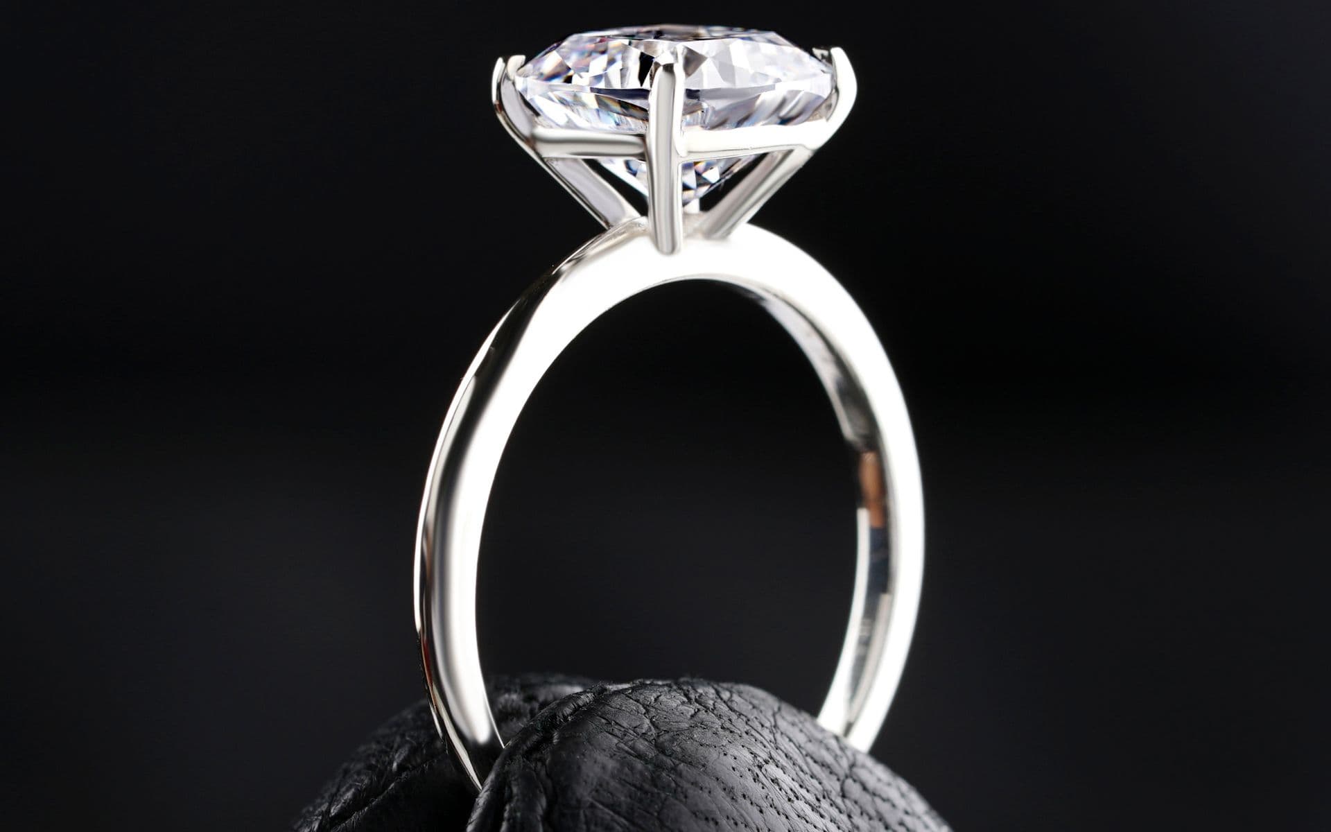 A solitaire diamond ring resting on dark stone